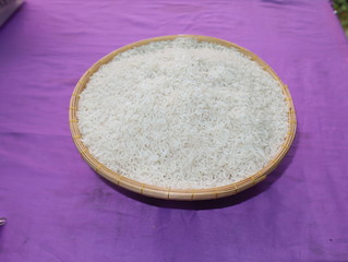 Rice in wooden bowl on purple background