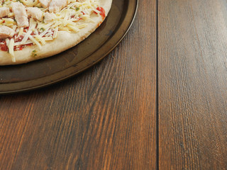 Uncooked raw pizza with chicken fillets cheese on a metal trey and wooden table, Ready to go in the oven. Copy space.