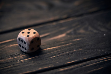 wooden dice on old wood table. number five on the top side.