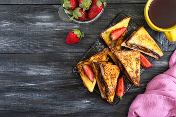 Sweet french toasts with banana, chocolate, strawberries on a wooden background. Tasty breakfast. Top view