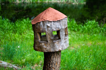 Wooden nest box for birds made with a tree trunk in a green forest