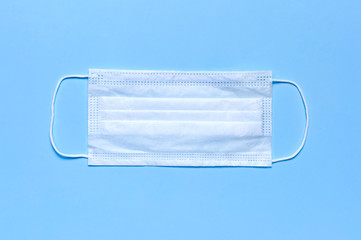 Medical mask on blue background flat lay top view with copy space. Protection against virus,...