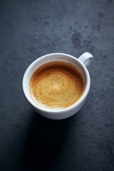 Cup of coffee on dark stone background. Close up. 