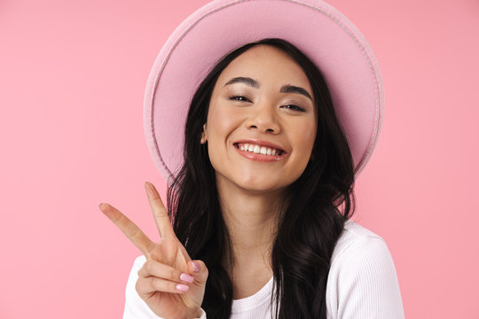 Image of young brunette asian woman smiling and showing peace fingers