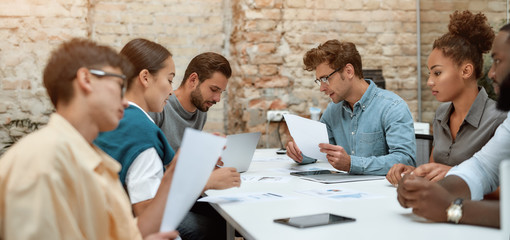 Successful startup team. Group of young business people discussing new project while sitting...