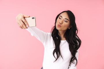 Image of young brunette asian woman smiling and taking selfie photo