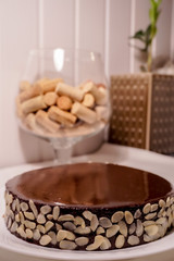 Chocolate cake with chocolate mirror glaze. With some almonds. On a background wine corks in a glass and flower. 