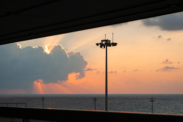 Panoramic view of sunset over the sea, with sunbeams in the clouds.