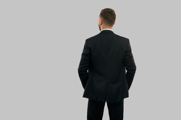 Back view of businessman with hands in pockets.