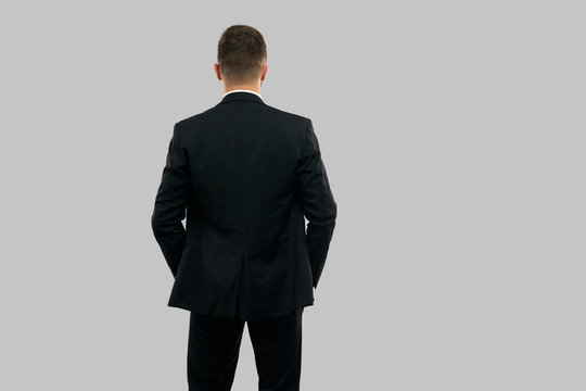 Back view of businessman with hands in pockets.