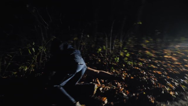 A man chasing a girl knocks her down to the ground, fighting against the background of the headlights of a car