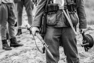 Rifle with a bayonet in the hands of a German soldier of the Second World War in full uniform on a black and white picture - obrazy, fototapety, plakaty