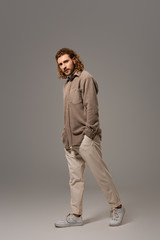 Obraz premium handsome man in shirt and trousers walking on grey background