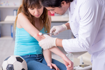 Fototapeta premium Young arm injured woman visiting young doctor traumatologist