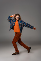 handsome man in shirt and trousers looking away on grey background