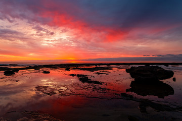 Fototapeta na wymiar Sunrise seascape at low tide with vivid reflections