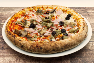 Pizza capricciosa, pizza alla capricciosa. Traditional italian pizza on wooden background