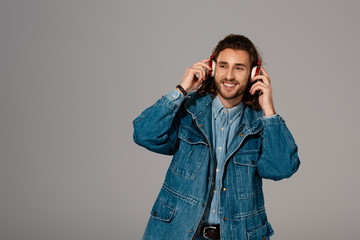 smiling man in denim jacket listening to music with headphones isolated on grey