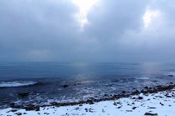 winter seascape evening on a stony snow covered shore