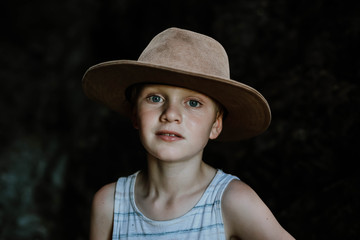 Moody image of young boy wearing hat in dark cave in tropical north Queensland