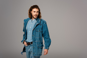 Fototapeta premium handsome and stylish man in denim jacket with hand in pocket isolated on grey