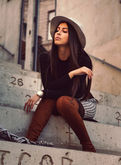 stylish girl model posing sitting on the steps of the building