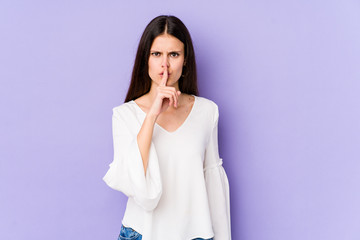 Young caucasian woman isolated on purple background keeping a secret or asking for silence.
