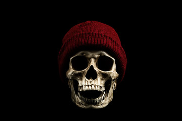 Scary human skull is wearing red knitted wool beanie hat.