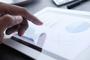 Fototapeta premium Businessman hand analyzing chart on digital tablet, closeup 