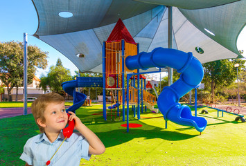 Blond boy speaks on red telephone