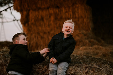 Brothers sitting together on haystack at winter time