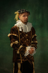 Posing thoughtful. Portrait of medieval young man in vintage clothing standing on dark background....