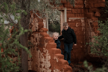 Two boys exploring ruins of fallen down mud brick house