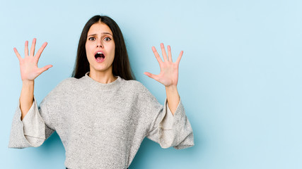 Young caucasian woman isolated on blue background screaming to the sky, looking up, frustrated.