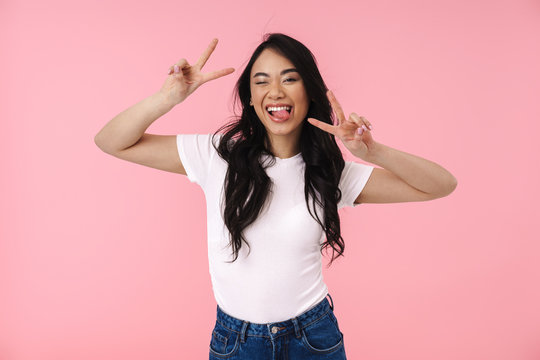 Image of young brunette asian woman smiling and showing peace fingers