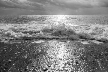 Black and white photography of beautiful sunny surface of sea water splashing at beach.