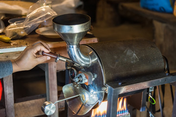 Roasted coffee bean pouring from roaster machine to cooling tray. Roasted process by coffee roaster...