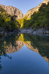 Fototapeta na wymiar Hdr vertical photo of beautiful mountain landscape with peaceful calm surface of river in foreground.