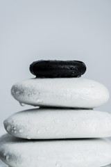 Macro shot of black and white zen stones in water drops isolated on grey