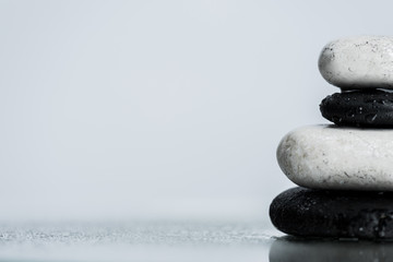 Close up view of water drops on zen stones on wet glass isolated on grey