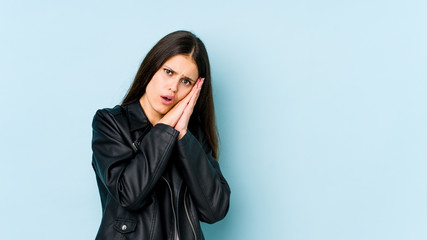 Young caucasian woman isolated on blue background yawning showing a tired gesture covering mouth with hand.