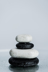 White and black zen stones on wet glass isolated on grey