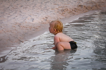 Baby boy in splashing in resort pool