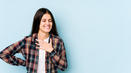 Fototapeta premium Young caucasian woman isolated on blue background laughing keeping hands on heart, concept of happiness.