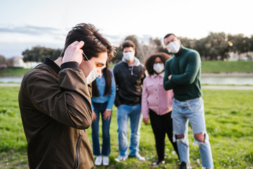 Obraz premium Group of teenagers friends at park wearing medical masks to protect from infections and diseases - Conceptual Coronavirus virus quarantine - Copy space - Multiracial people having fun together