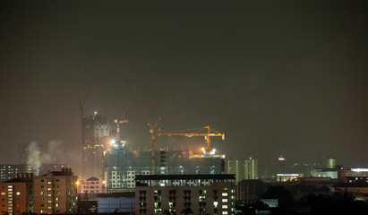 night in the city, with cranes running on high buildings