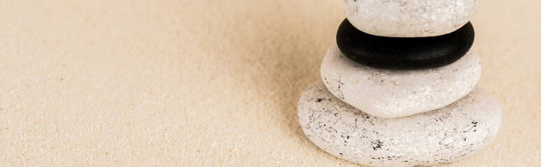 Panoramic shot of zen stones on sand surface with copy space