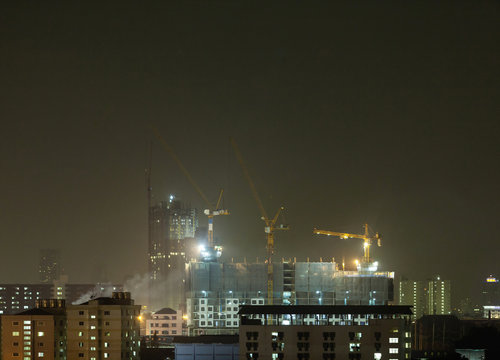 night in the city, with cranes running on high buildings