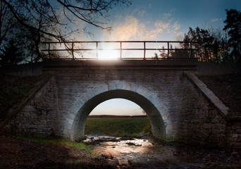 Old stone tunnel, railway bridge with small brook, sunset mood, symbol of entrance or change