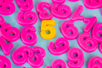 Yellow five number and pink plastic numbers on blue background